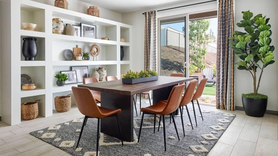 Modern dining room with built-in shelving and large window for natural light Model home with a fiddle leaf fig and box of succulents