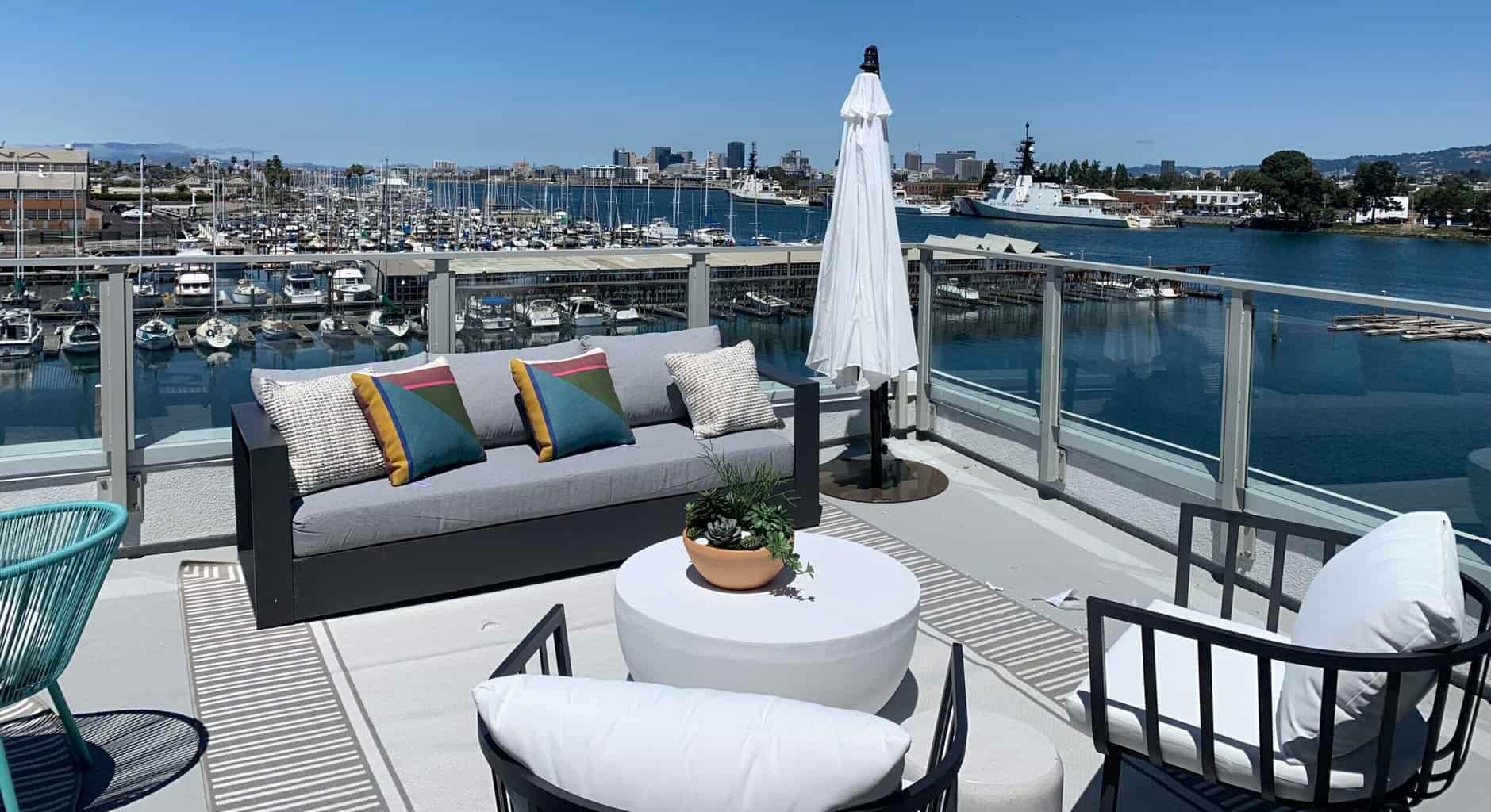 Dockside outdoor patio with contemporary furniture overlooking marina and sailboats.